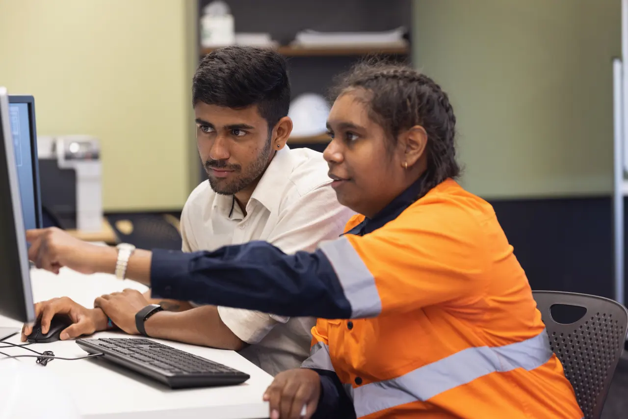 Two people reviewing a computer screen at a workstation.